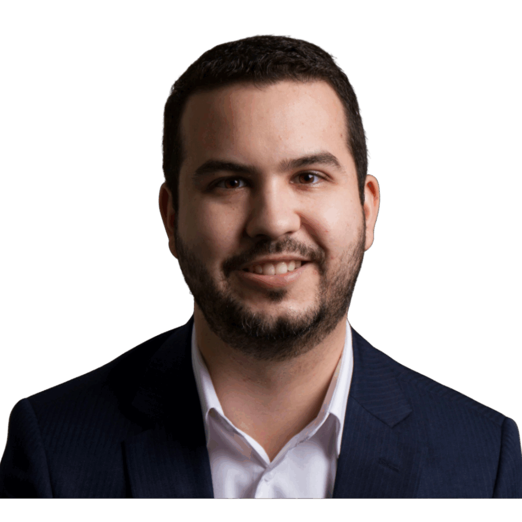 Foto retrato de Vitor Campos, especialista em finanças e criador do Protocolo Renda+. O autor sorri usando camisa branca e terno azul em fundo neutro, transmitindo confiança e profissionalismo.